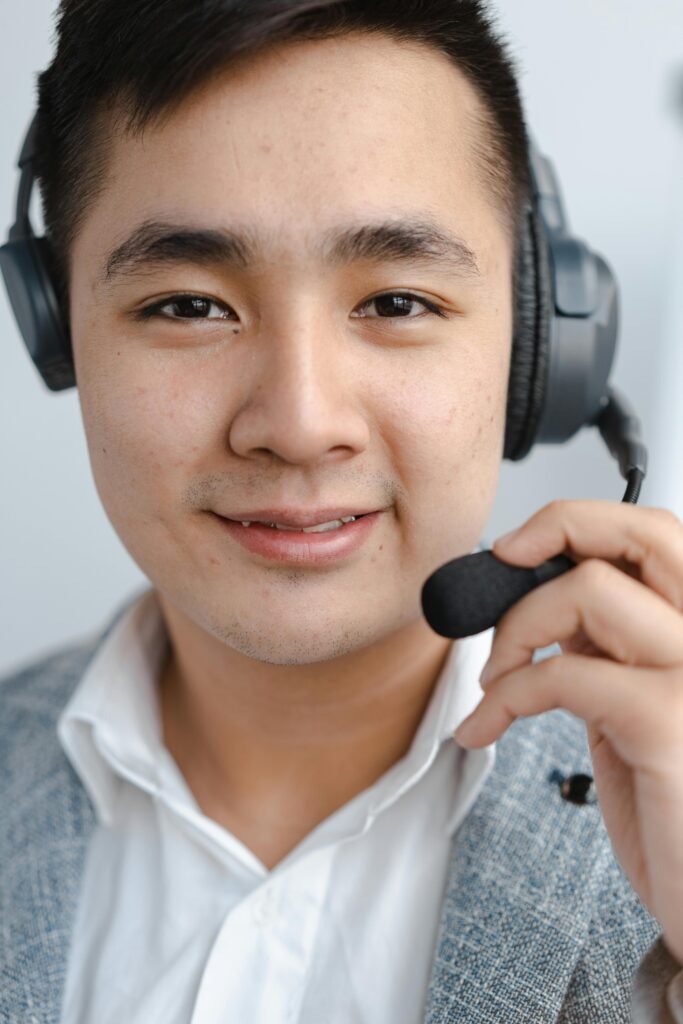 Close-up of a call center agent smiling while wearing a headset microphone.